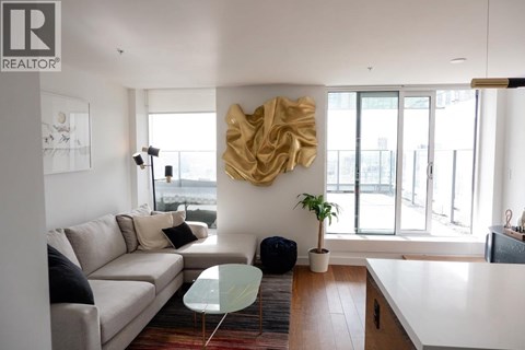 A living room with a couch, a table, and a large sculpture on the wall.