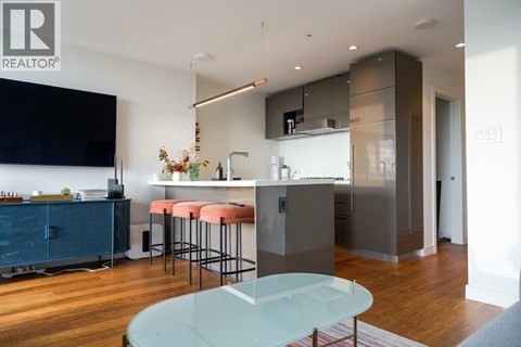 A modern kitchen with a glass table and bar stools.