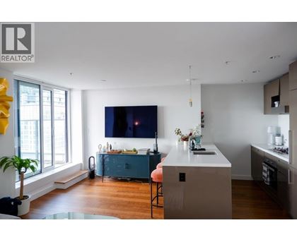 A modern kitchen with a blue island and a flat screen TV mounted on the wall.