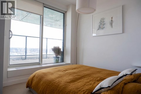 A bedroom with a large bed and a window overlooking a snowy landscape.