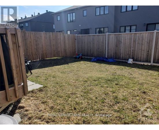 A backyard with a wooden fence and a blue tarp on the ground.