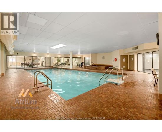 A large indoor swimming pool with a tiled floor and a diving board.