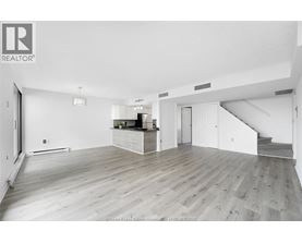A spacious living room with wooden flooring and white walls.