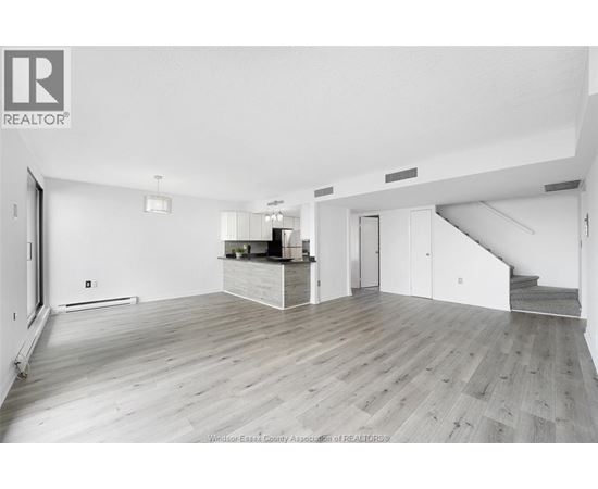 A spacious living room with wooden flooring and white walls.