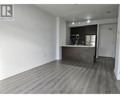 A spacious room with a kitchenette in the background.