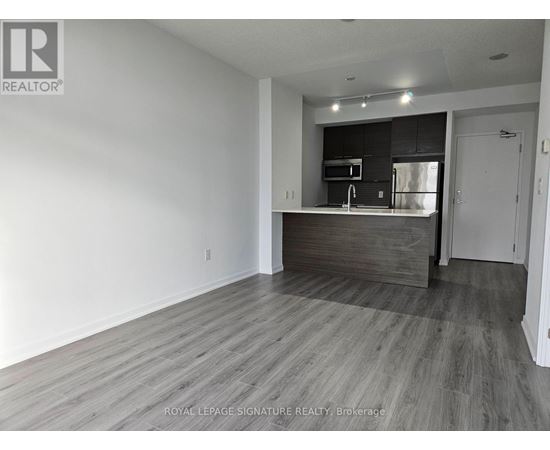 A spacious room with a kitchenette in the background.