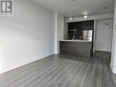 A spacious room with a kitchenette in the background.