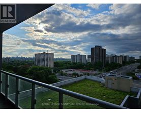 A view from a balcony overlooking a cityscape with a green space in the foreground.