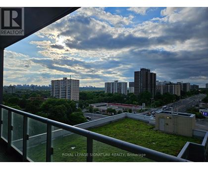 A view from a balcony overlooking a cityscape with a green space in the foreground.