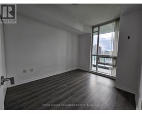 A room with wooden flooring and a sliding glass door leading to a balcony.