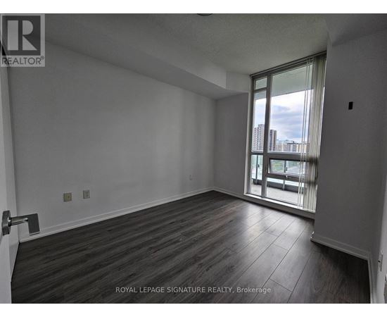 A room with wooden flooring and a sliding glass door leading to a balcony.