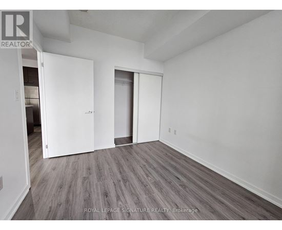 A room with white walls and wooden flooring, with two doors and a ceiling fan.