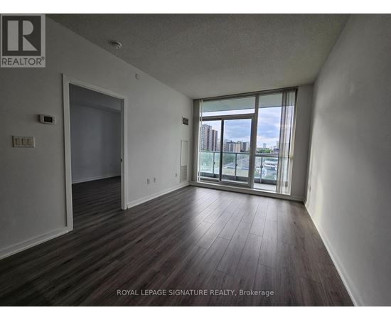 A room with wooden flooring and a sliding glass door leading to a balcony.