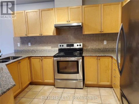 A kitchen with wooden cabinets and a stainless steel refrigerator.
