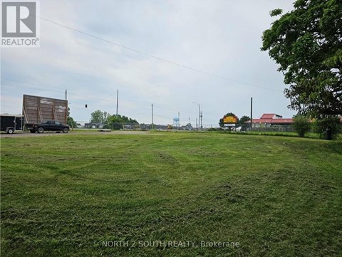A grassy field with a truck and a building in the background.