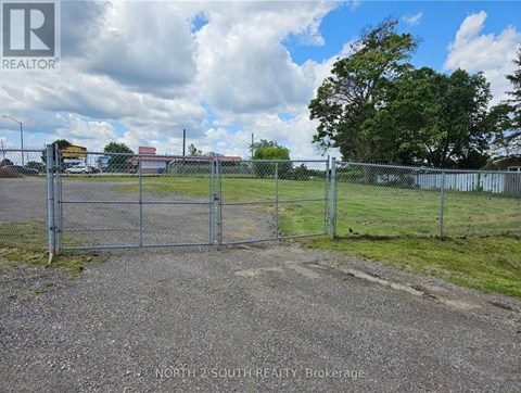 A gate leads to a fenced area in a sunny day.