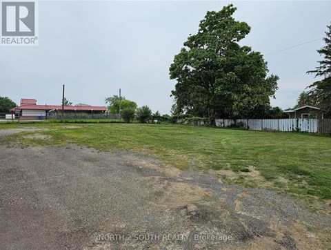 A grassy field with a fence and a building in the background.