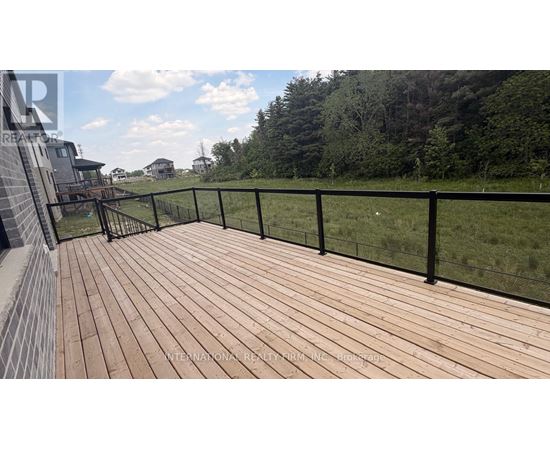 A wooden deck with a black railing overlooks a grassy area.