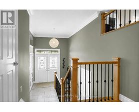 A hallway with a white door and a staircase with a wooden banister.