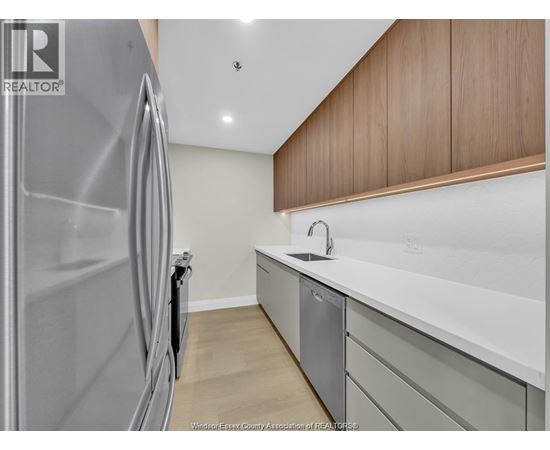 A modern kitchen with a stainless steel refrigerator and wooden cabinets.