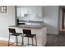A kitchen with a granite countertop and two black barstools.