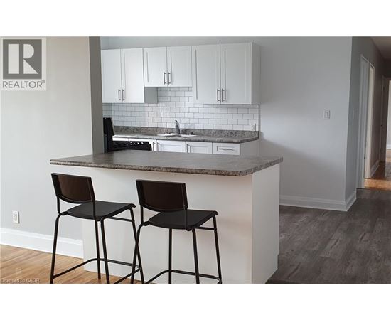 A kitchen with a granite countertop and two black barstools.