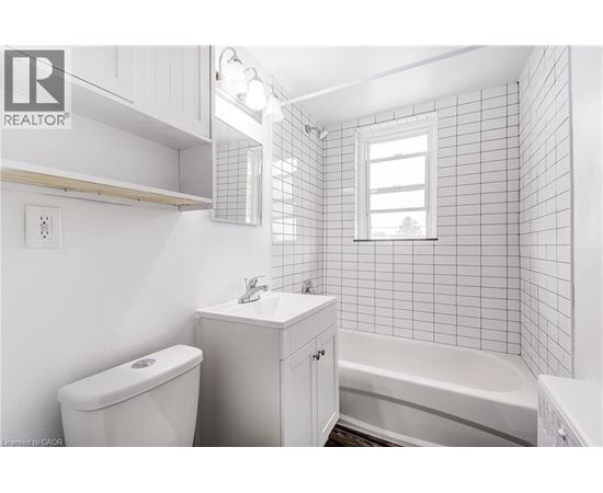 A white bathroom with a toilet, sink, and bathtub.