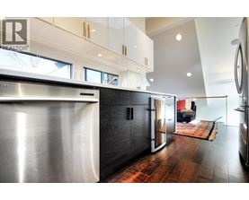 A modern kitchen with a stainless steel refrigerator and wooden floors.