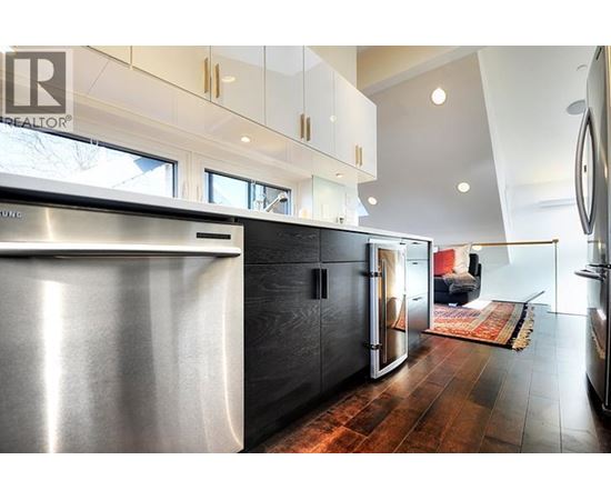 A modern kitchen with a stainless steel refrigerator and wooden floors.