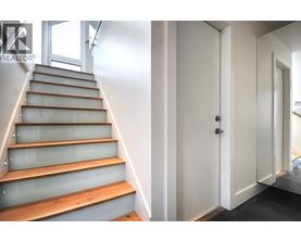A set of stairs with a glass balustrade and wooden steps leading to a white door.