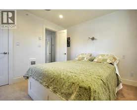 A bedroom with a bed, a door, and a wall-mounted fan.