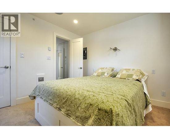 A bedroom with a bed, a door, and a wall-mounted fan.