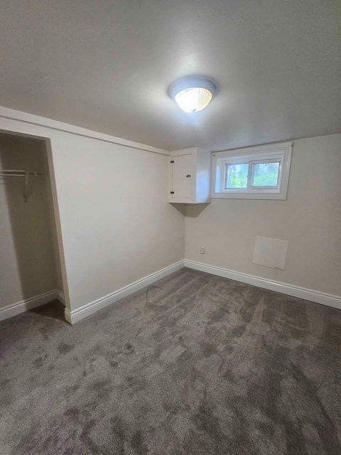 A room with a grey carpet and a small window.
