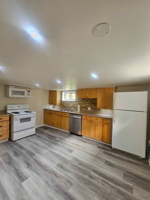 A kitchen with a white refrigerator, white stove, and wooden cabinets.