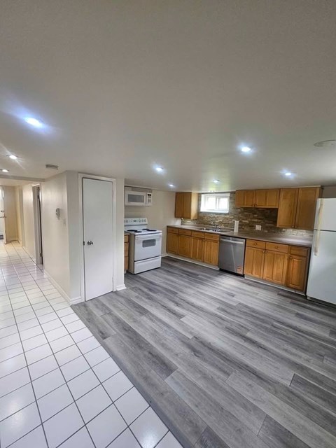 A kitchen with white appliances and wooden cabinets.