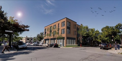A street view of a building with cars and birds in the sky.