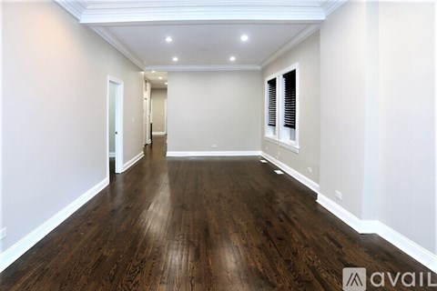 A spacious room with wooden flooring and white walls.