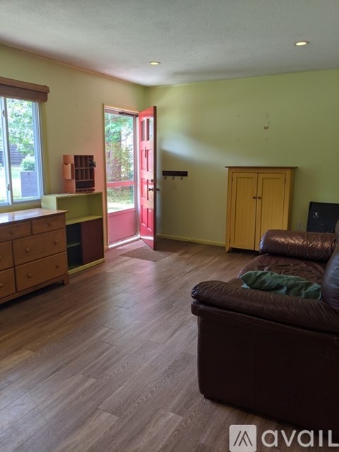 A living room with a brown couch and a wooden cabinet.