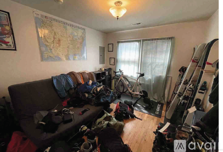 A room with a map on the wall and a couch covered in bags.