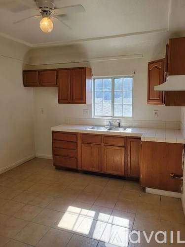 A kitchen with wooden cabinets and a ceiling fan.