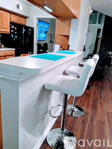 A kitchen with a white bar stool in front of a white counter.
