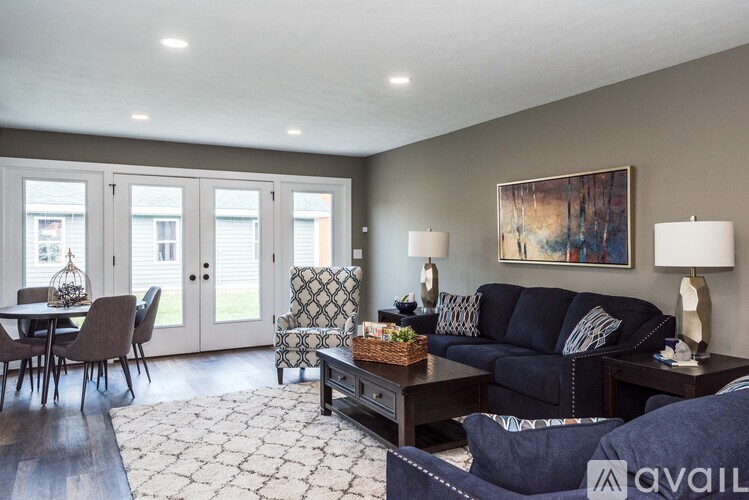 A living room with a sofa, chairs, and a painting on the wall.