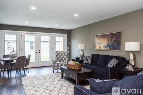 A living room with a sofa, chairs, and a painting on the wall.