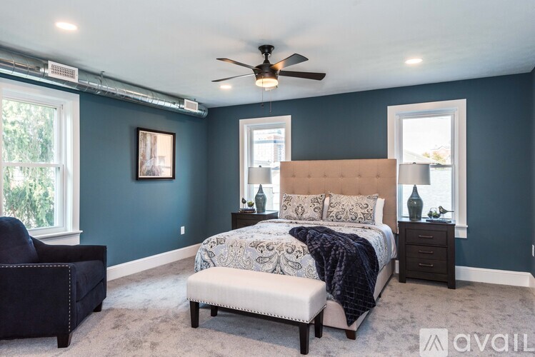 A bedroom with a bed, a chair, and a ceiling fan.