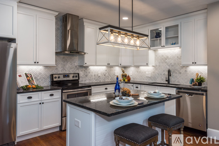 A kitchen with white cabinets and a black countertop.