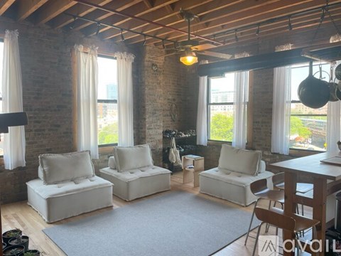 A living room with white furniture and a brick wall.