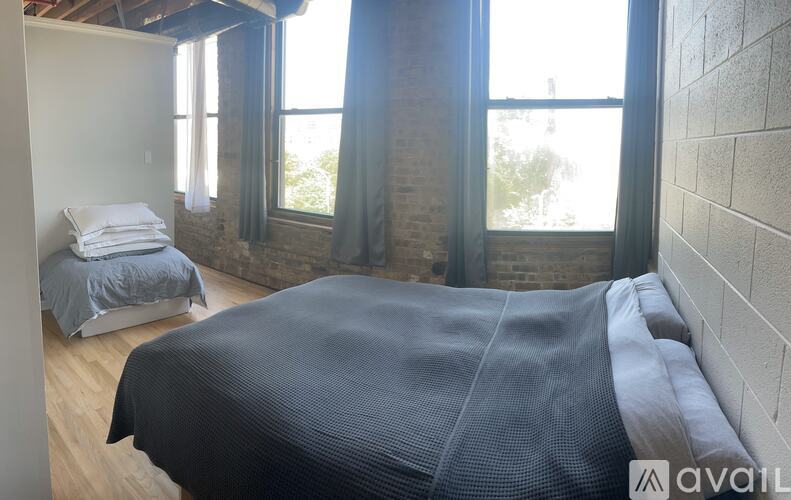 A bedroom with a large bed and a window with curtains.