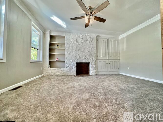 A living room with a fireplace and a ceiling fan.