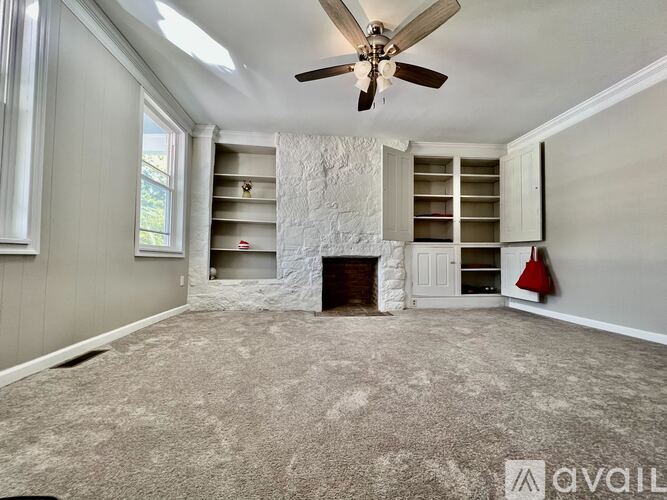 A spacious room with a fireplace and built-in shelves.