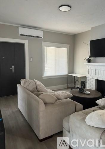 A living room with a couch, a chair, and a fireplace.